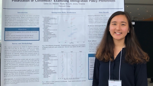 A young woman stands in front of a conference poster